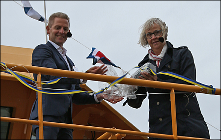 Flaskan väl draperad i plast överräcks till gudmor Lena Erixson.